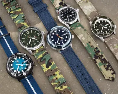 A variety of watches with different straps displayed on a surface, showcasing styles ranging from casual to military, ideal for matching with various outfits