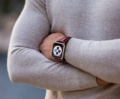 A close-up of a person's arm crossed over their chest, showcasing a stylish watch with a brown strap against a neutral sweater background. Perfect for unique watch strap styling tips