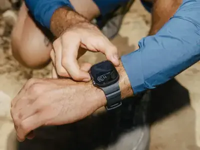 A person adjusts a fitness watch on their wrist while outdoors, showcasing a focus on selecting the ideal strap for an active lifestyle