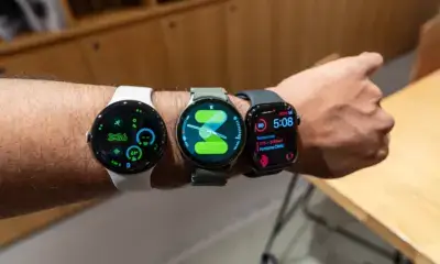 Three smartwatches with different straps displayed on a person's wrist, showcasing various designs and features against a wooden background