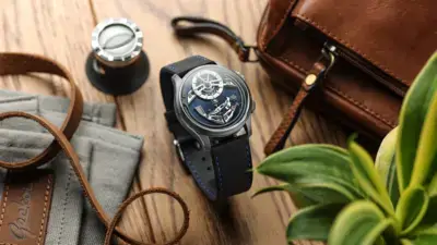 A stylish watch with a blue strap is placed on a wooden surface alongside a brown leather bag, a measuring tool, and a green plant, showcasing a blend of elegance and practicality