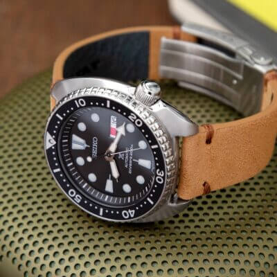 A close-up of a Seiko watch featuring a black dial and a brown leather quick-release band, showcasing modern design and functionality