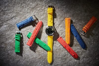 A smartwatch surrounded by colorful waterproof straps on a textured surface, showcasing various options for style and functionality