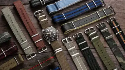 A variety of watch straps displayed on a wooden surface, showcasing classic leather, modern nylon, and stylish fabric designs in multiple colors and patterns