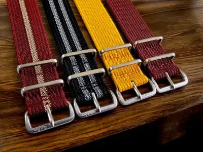 A collection of nylon straps in various colors, featuring metal buckles, displayed on a wooden surface, showcasing their versatility for smartwatches