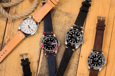 A collection of wristwatches featuring various leather straps displayed on a wooden surface, highlighting the historical significance and craftsmanship of leather in watchmaking