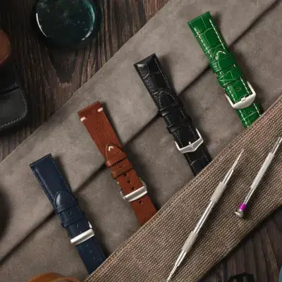 A variety of watch straps in different colors and materials displayed on a textured surface, with watch tools nearby, illustrating options for choosing the right buckle