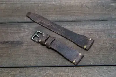 Brown leather smartwatch straps with a metallic buckle, laid out on a wooden surface. Ideal for a stylish and rugged look for pilots and aviation enthusiasts