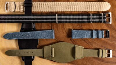 A variety of watch straps displayed on a wooden surface, showcasing different materials including leather, fabric, and metal, ideal for various lifestyles