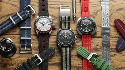 A variety of watch straps displayed on a wooden surface, showcasing materials like silicone, leather, and fabric, ideal for sensitive skin