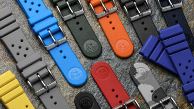 A variety of colorful rubber watch straps displayed on a textured surface, showcasing different colors and styles for maintaining durability and style