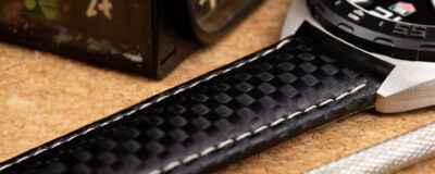 Close-up of a carbon watch strap on a textured surface, showcasing its unique pattern and stitching, ideal for a guide on cleaning and maintenance tips