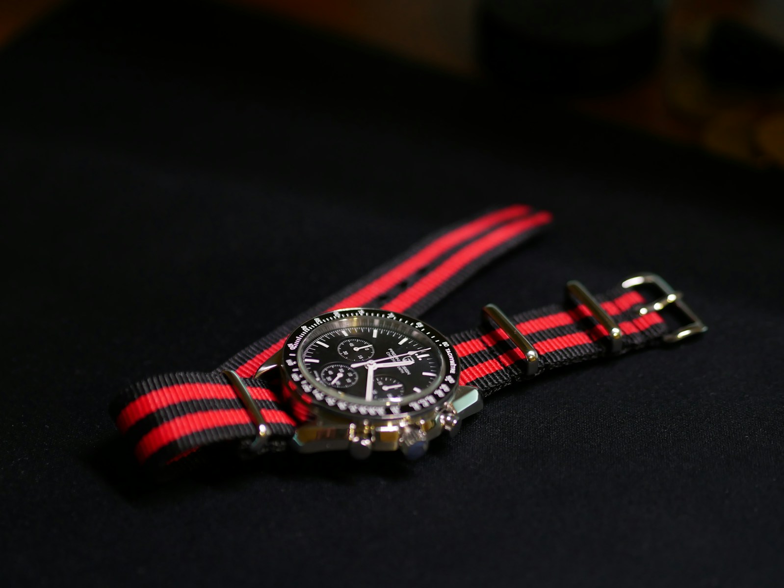 A watch with a red and black striped strap