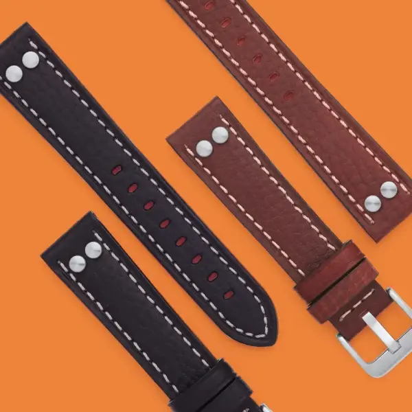 A collection of pilot watch bands in black and brown leather, featuring contrasting stitching and metal buckles, displayed against an orange background