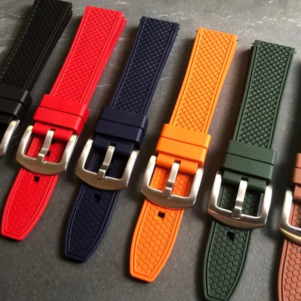 A collection of FKM watch straps in various colors, including black, red, blue, orange, green, and brown, displayed on a textured surface