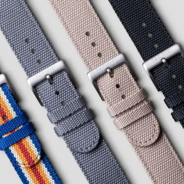 A collection of quick release straps in various colors, including blue with stripes, gray, beige, and black, displayed against a neutral background