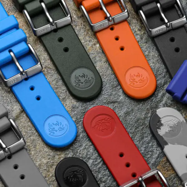 A variety of colorful rubber watch straps displayed on a textured surface, showcasing different colors and styles for maintaining durability and style