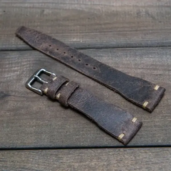 Brown leather smartwatch straps with a metallic buckle, laid out on a wooden surface. Ideal for a stylish and rugged look for pilots and aviation enthusiasts