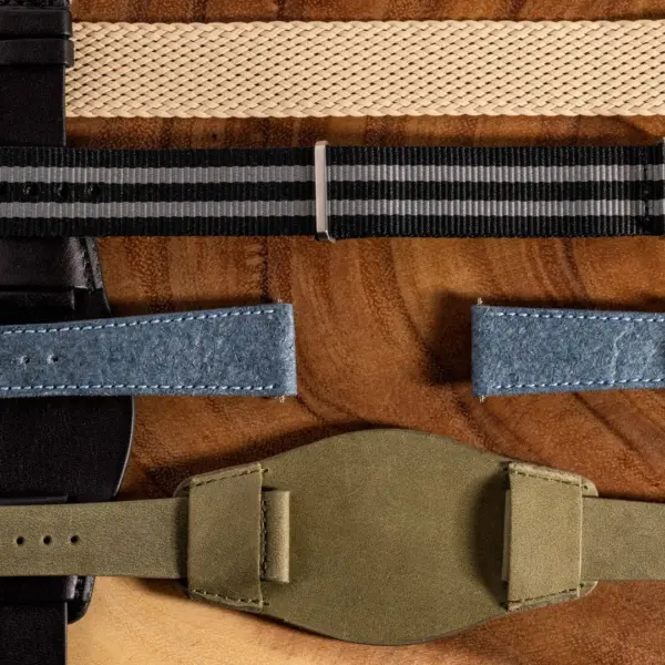 A variety of watch straps displayed on a wooden surface, showcasing different materials including leather, fabric, and metal, ideal for various lifestyles