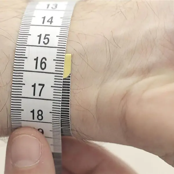 A close-up of a hand measuring a wrist with a flexible measuring tape, highlighting the importance of accurate measurements for a perfect watch strap fit