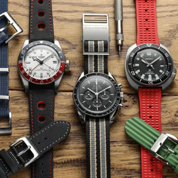 A variety of watch straps displayed on a wooden surface, showcasing materials like silicone, leather, and fabric, ideal for sensitive skin