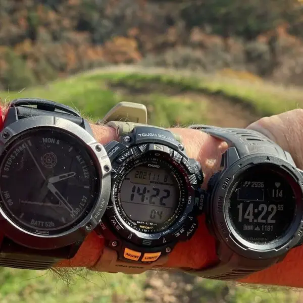A close-up of a person's wrist showcasing three different waterproof watch bands, set against a scenic outdoor background, ideal for adventurers