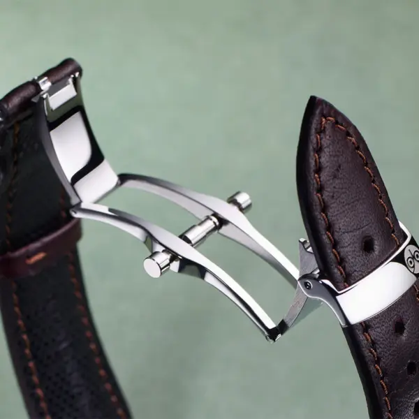 A close-up of a deployant clasp showcasing its sleek design and craftsmanship, featuring a polished metal finish and a leather watch strap