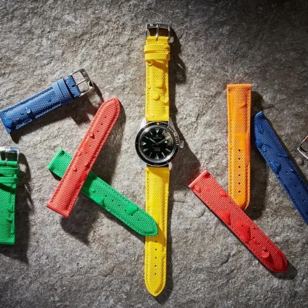 A smartwatch surrounded by colorful waterproof straps on a textured surface, showcasing various options for style and functionality