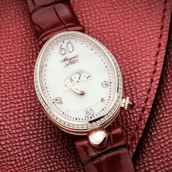 A close-up of an elegant watch with a white face and diamond accents, resting on a rich red leather background, perfect for a romantic date night accessory