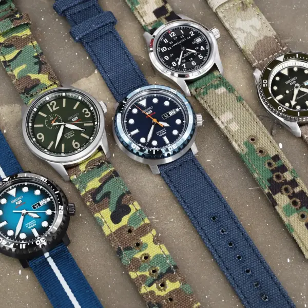A variety of watches with different straps displayed on a surface, showcasing styles ranging from casual to military, ideal for matching with various outfits