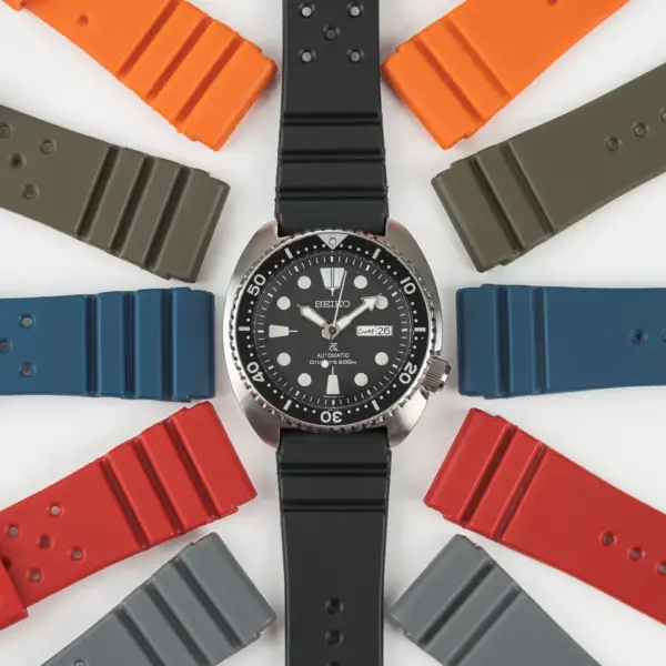 A black rubber watch strap is surrounded by colorful rubber straps in orange, red, blue, gray, and green, showcasing options for customizing a watch
