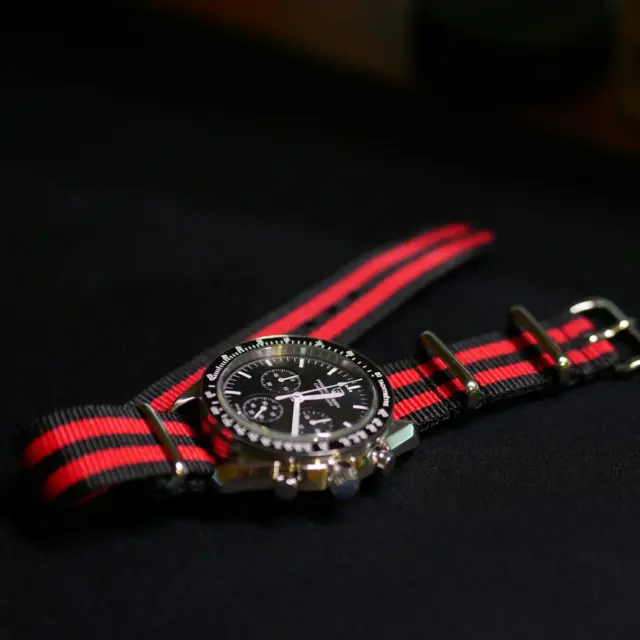 A watch with a red and black striped strap