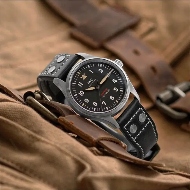 A stylish pilot watch with a black dial and leather strap, set against a backdrop of textured brown leather, showcasing contemporary fashion versatility