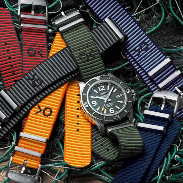 A collection of colorful nylon watch bands in various patterns, arranged around a classic metal watch, set against a backdrop of tangled green fishing nets