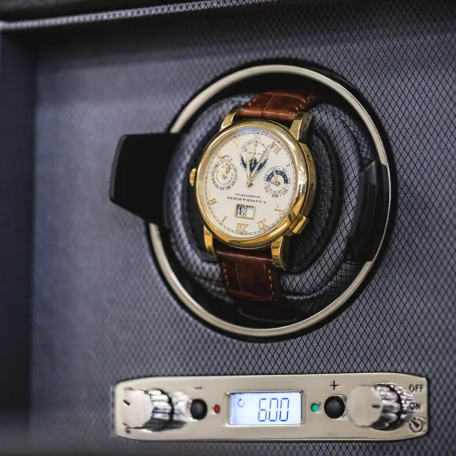 A close-up of a luxury watch resting in a watch winder, showcasing a manual and automatic winding mechanism with digital display settings